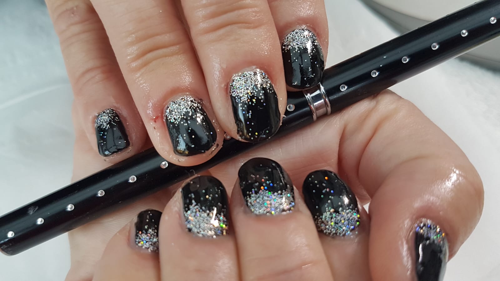 Glossy black nails finished with silver glitter